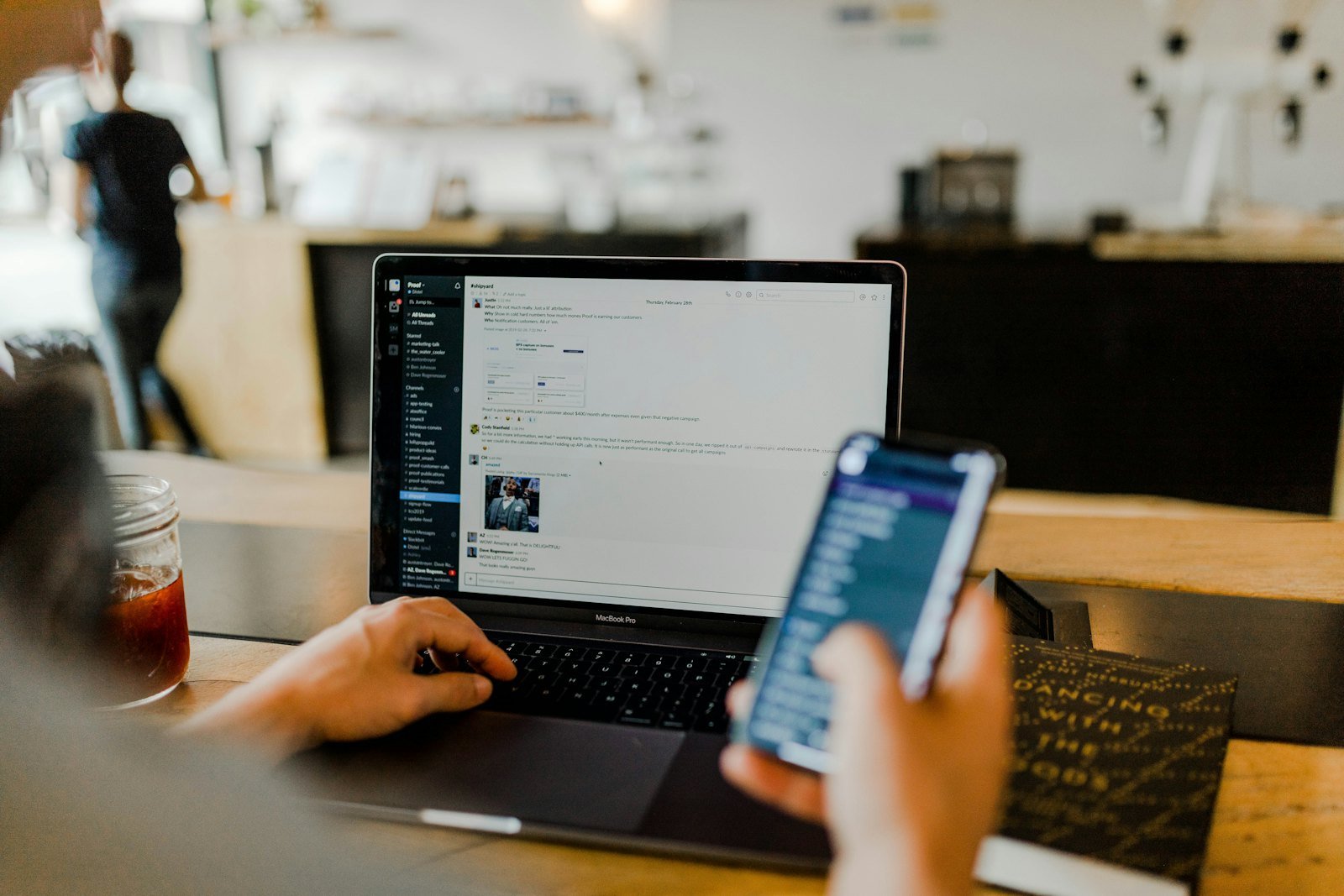 Hands using a laptop and a phone side by side to review a document