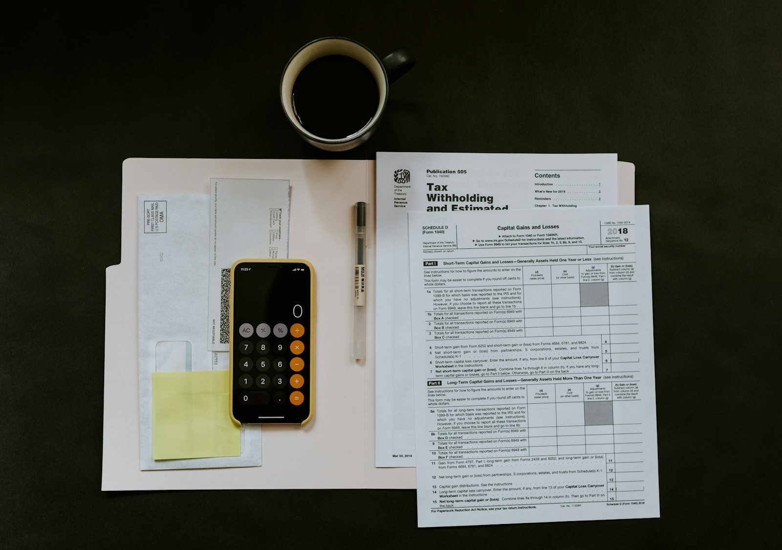 Printed forms and a calculator spread across a dark desk