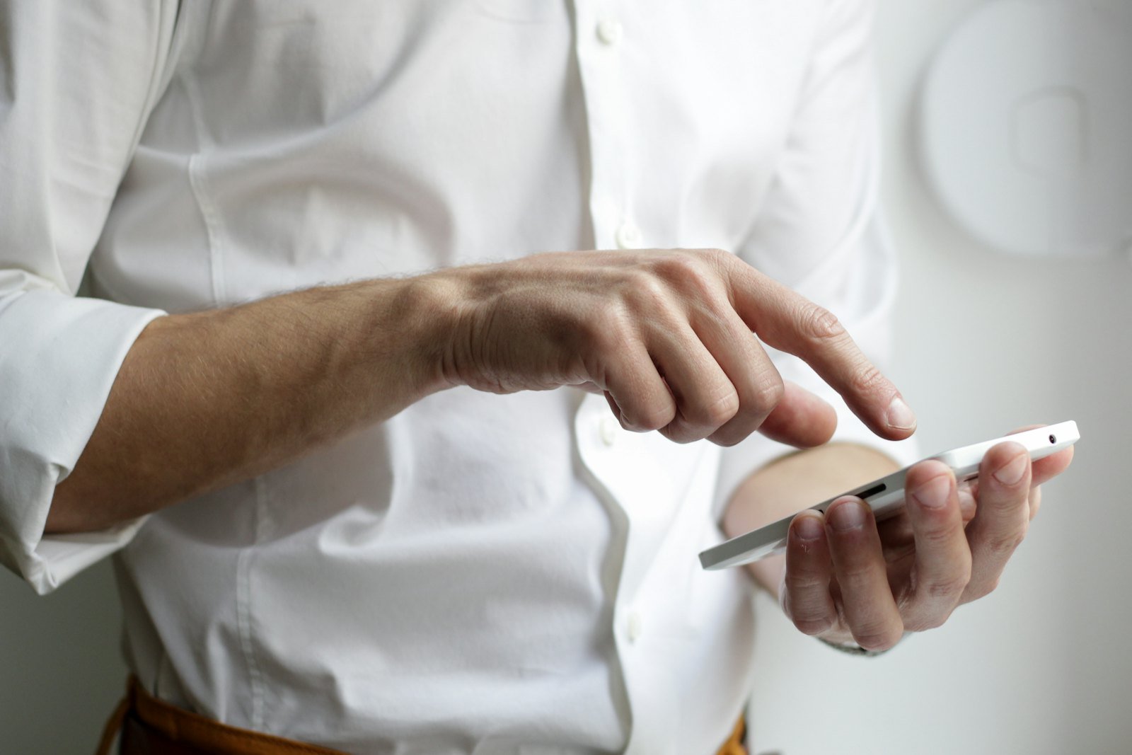 A person holding a smartphone in one hand, reading it closely