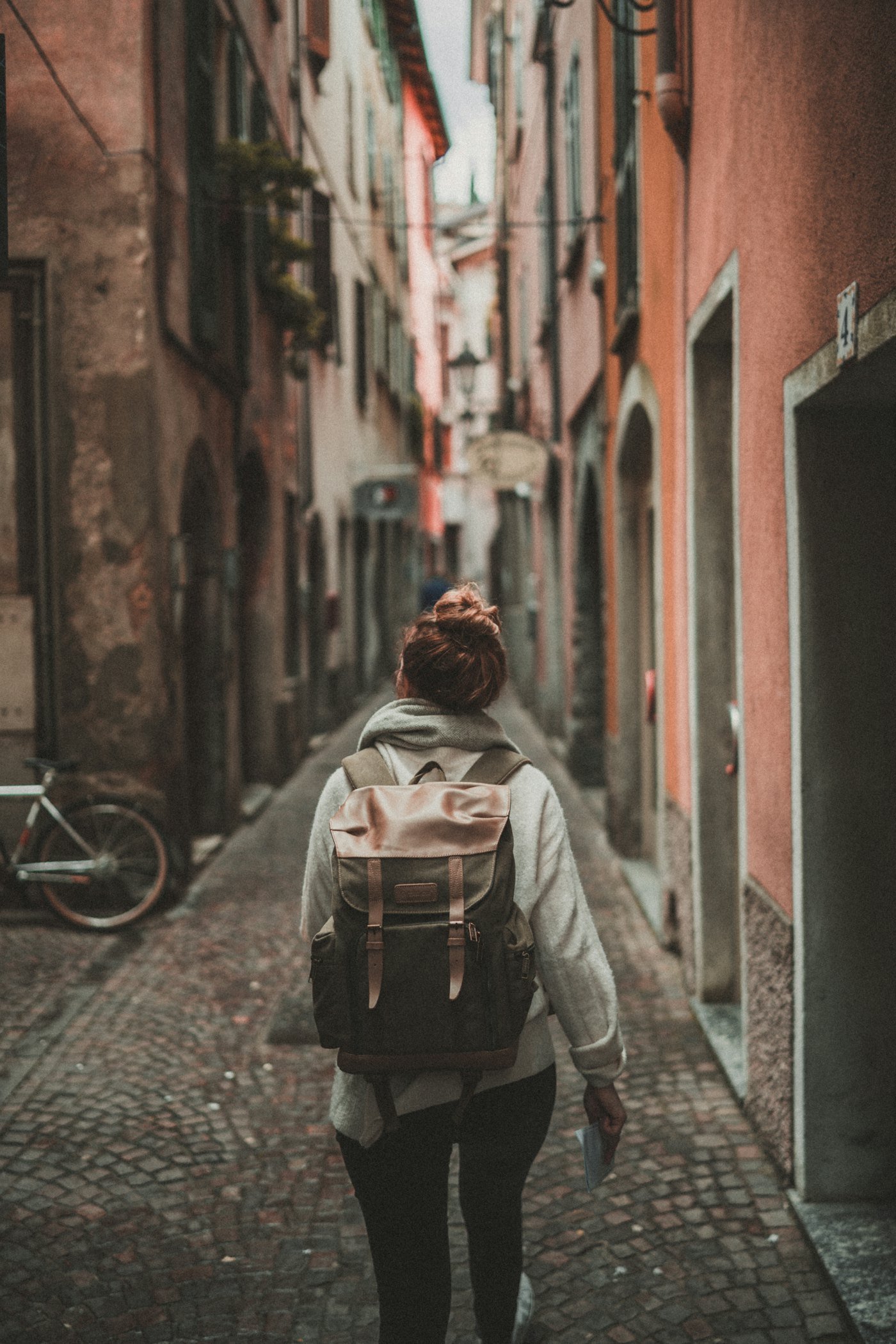A traveller with a backpack walking alone down a narrow street